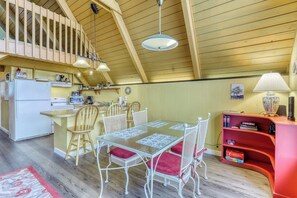 A cozy kitchen with a dining area, wooden ceiling, and a red bookshelf. - 1BR A-frame oceanfront (Anacortes)