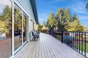 A wooden deck with a glass door leading to a covered area, surrounded by a black metal fence.