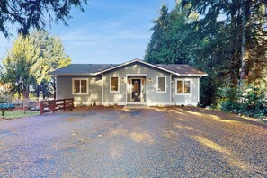 A single-story house with a front porch, a gravel driveway, and a wooden fence.