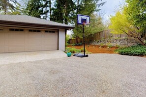 Ein Einfahrt mit Basketballkorb, Garage und einer Mauer aus Natursteinen.