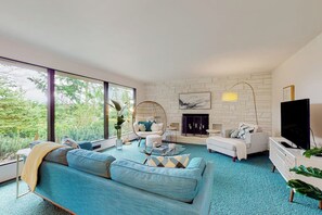 Ein modernes Wohnzimmer mit Sofa, Sesseln, Couchtisch, Kamin und Fernseher.