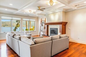 A spacious living room with a large sectional sofa, a fireplace, and a view of a lake. - Lovely 3BR Lakefront - Dock - Fireplace (Bellingham)