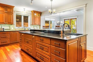 A kitchen with wooden cabinets, a large island, and a view to a dining area. - Lovely 3BR Lakefront - Dock - Fireplace (Bellingham)