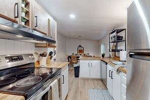 A modern kitchen with a built-in oven, white cabinets, and a stainless steel refrigerator. - 3BR Farmhouse with water views, wifi (Shelton)