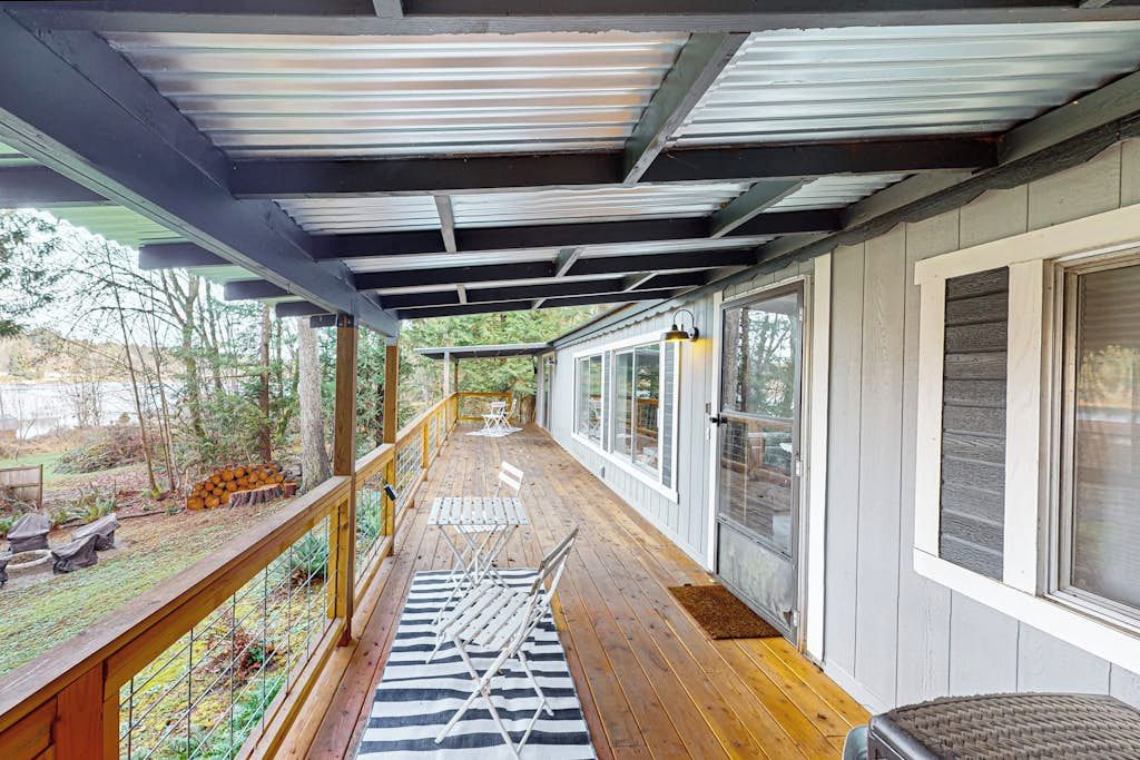Eine überdachte Veranda mit Holzboden, Metallgeländer und Blick ins Freie.