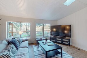 A modern living room with a sofa, coffee table, and a flat-screen TV. - 3BR Farmhouse with water views, wifi (Shelton)