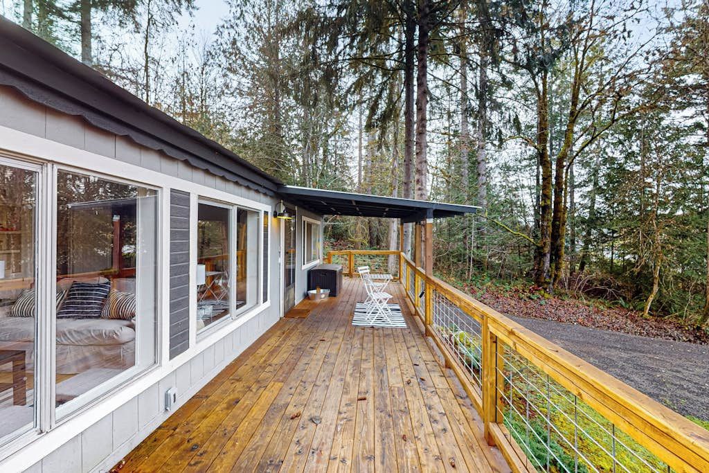 A wooden deck with a railing, a sofa, and a table, surrounded by trees.