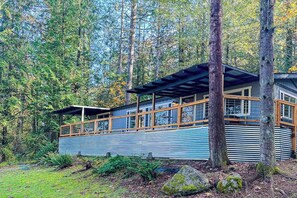 A cabin with a covered porch, surrounded by trees. - 3BR Farmhouse with water views, wifi (Shelton)