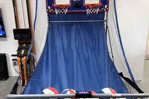 Ein Basketballkorb mit blauem Netz und zwei Basketballs auf dem Boden.