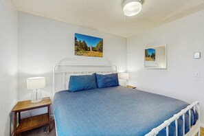 Ett sovrum med en säng, två sängbord, ett litet bord och två vägglampor.