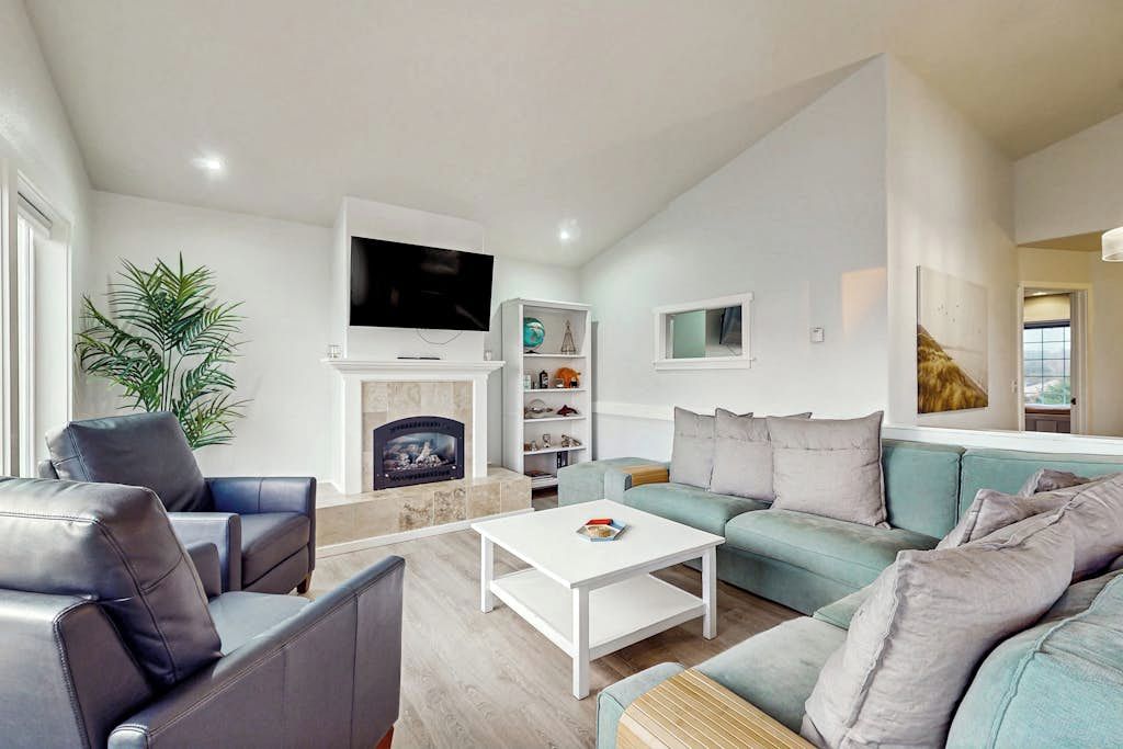 Een moderne woonkamer met een open haard, een flatscreen-tv, een bank en een salontafel.