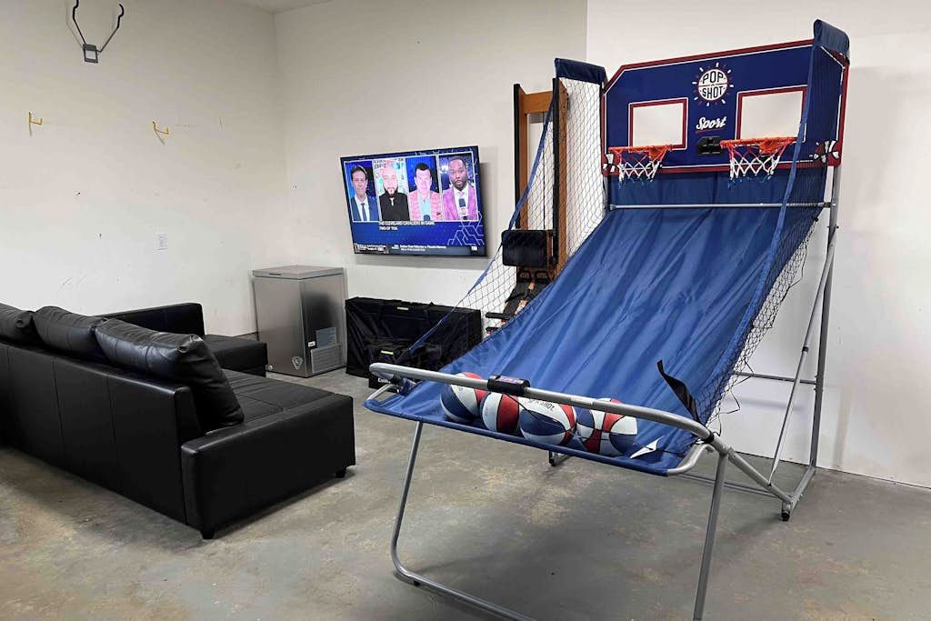 A room with a blue trampoline, a black sofa, and a television mounted on the wall.