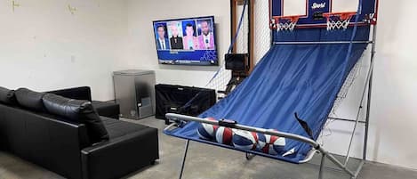 A room with a blue trampoline, a black sofa, and a television mounted on the wall.