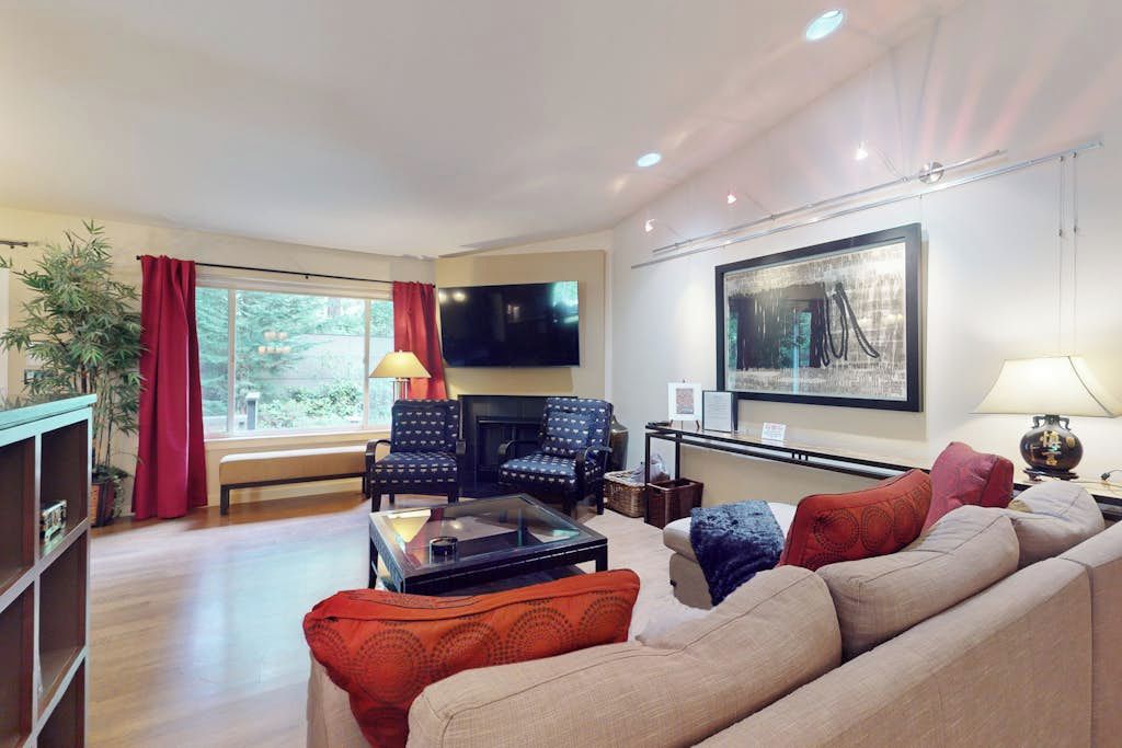 A living room with a sofa, armchairs, a coffee table, a TV, and a fireplace.