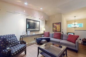 A living room with a sofa, armchair, and coffee table. There are paintings on the wall and a chandelier. - Forest 3BR in Shoreline with patio & yard (Shoreline)