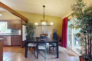 A dining area with a table and chairs, a chandelier, and a view of the outdoors. - Forest 3BR in Shoreline with patio & yard (Shoreline)