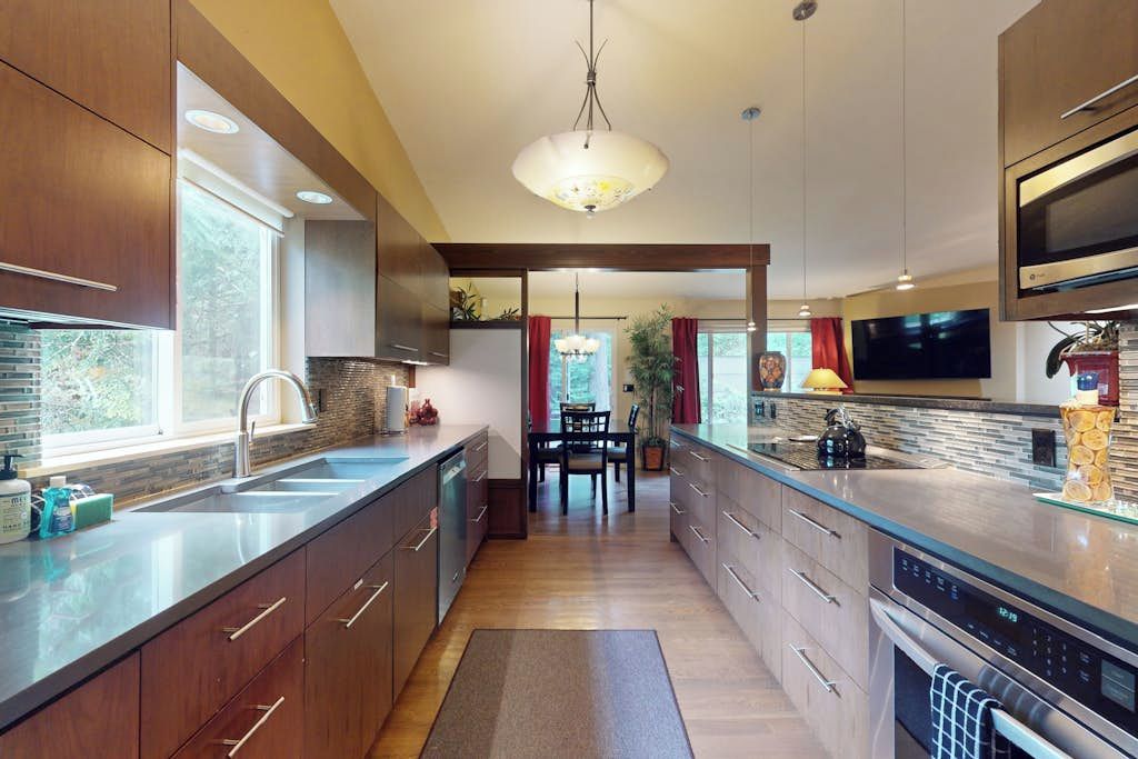 A modern kitchen with a central island, built-in appliances, and a dining area with a chandelier.