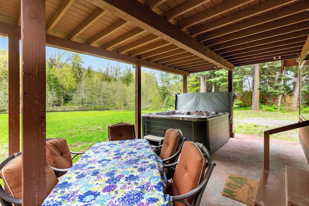 Eine Außenpatio mit Tisch und Stühlen, einem Whirlpool und Blick auf eine grüne Landschaft.