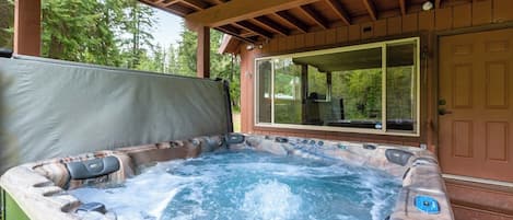 Un bain à remous doté d’une terrasse en bois et d’une porte en verre.