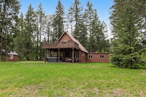 A cabin with a porch, surrounded by a grassy area and tall trees. - Large 3BR Riverfront Dog Friendly - Hot Tub (Easton)