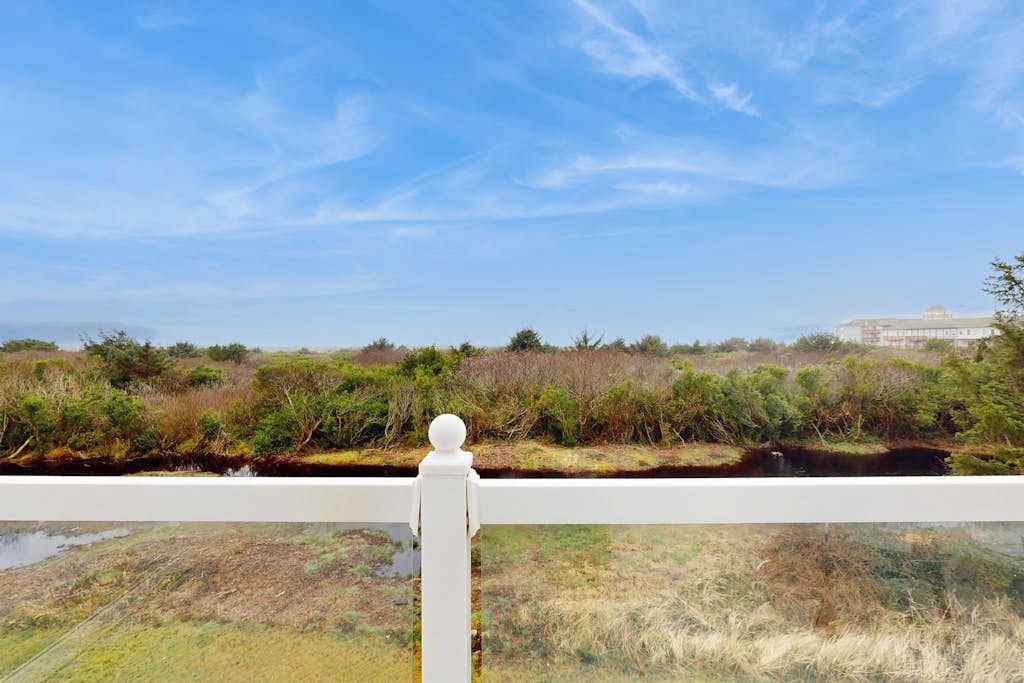 Vista de varanda com guarda-corpo, com paisagem natural, corpo d'água e vegetação.