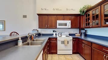 A kitchen with wooden cabinets, a white stove, a microwave, and a sink.