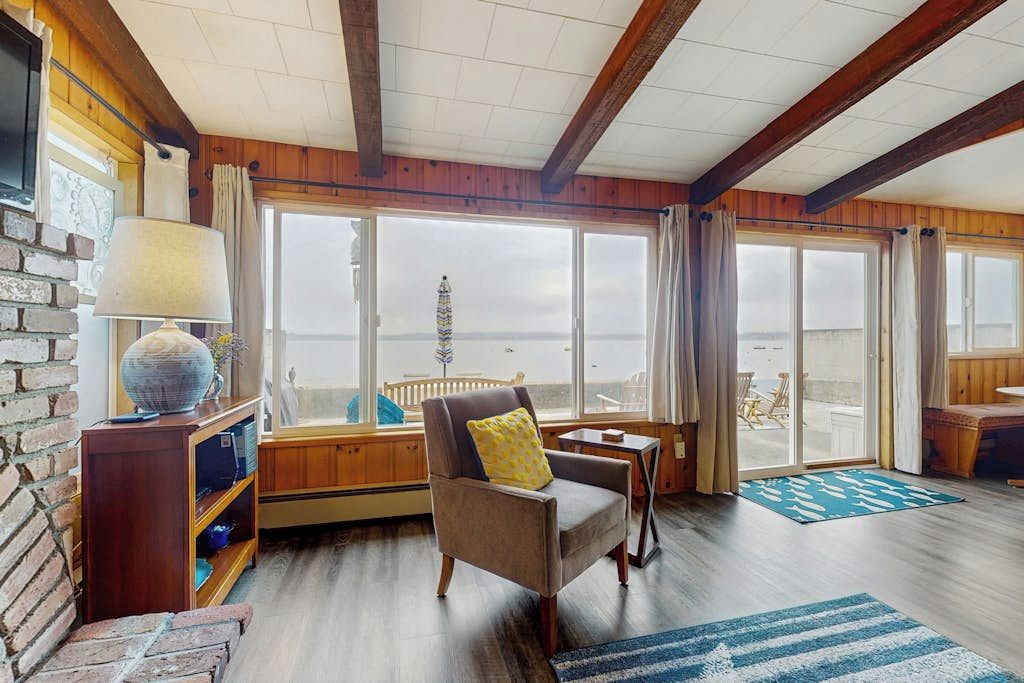 A cozy room with a large window, a comfortable chair, a small table, and a bookshelf.