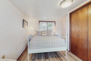 Ein Schlafzimmer mit einem Bett, Nachttischen, einem Fenster und einer Holztür.