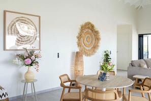 A modern living room with a round table, wicker chairs, and a large abstract artwork on the wall. - "Altura" | Luxury 3BR Penthouse by Mambo Beach (Willemstad)