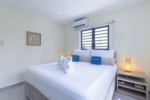 A hotel room with a bed, a nightstand, a lamp, and a window with blinds. - "Altura" | Luxury 3BR Penthouse by Mambo Beach (Willemstad)