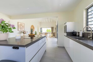 Une cuisine moderne dotée d’un îlot central, d’appareils électroménagers intégrés et donnant sur un espace repas.