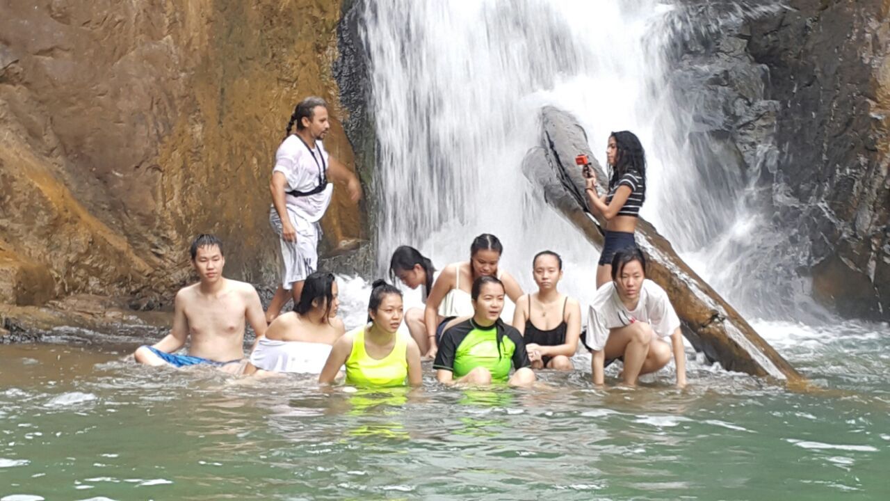 Een groep mensen in een natuurlijke omgeving met een waterval en rotsachtig terrein.