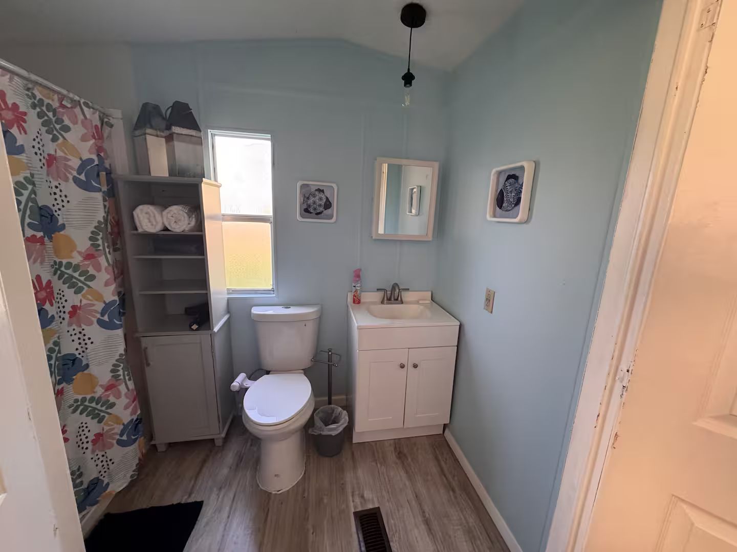 Een kleine badkamer met toilet, wastafel en een douchegordijn met bloemenprint.