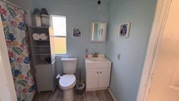 Een kleine badkamer met toilet, wastafel en een douchegordijn met bloemenprint.