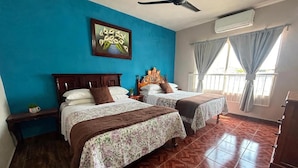 A hotel room with two beds, a ceiling fan, an air conditioning unit, and a window with curtains. - Bugambilia - Cozy Apartment 8 Minutes from the Beach (Veracruz)