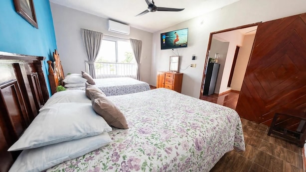 A hotel room with two beds, a television, an air conditioning unit, and a wooden door. - Bugambilia - Cozy Apartment 8 Minutes from the Beach (Veracruz)