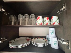 Un meuble de cuisine contenant de la verrerie, des assiettes et des tasses.