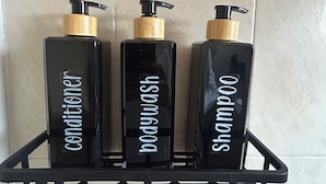 Three black bottles with pump dispensers on a black shelf against a tiled wall. - Bugambilia - Cozy Apartment 8 Minutes from the Beach (Veracruz)