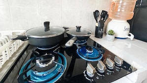 A kitchen with a gas stove, pots, a water dispenser, and a small potted plant. - Bugambilia - Cozy Apartment 8 Minutes from the Beach (Veracruz)