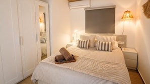 Une chambre à coucher comprenant un lit, une armoire, une table de chevet et une lampe fixée au mur.