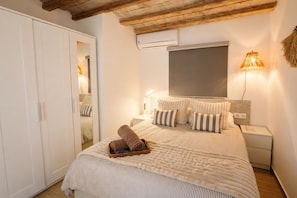 Ein Schlafzimmer mit einem Bett, einem Kleiderschrank, einem Nachttisch und einer Wandlampe.