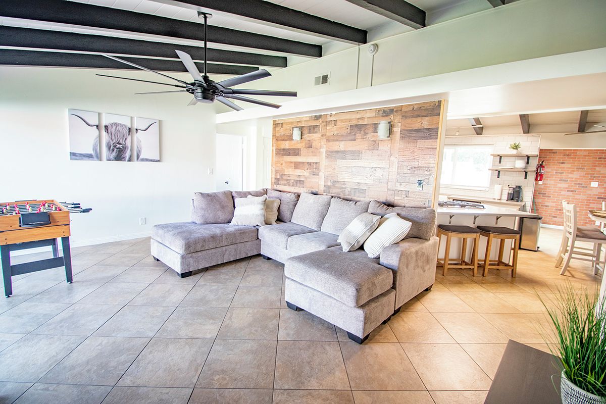 A modern living room with a sectional sofa, a foosball table, and a kitchen area with bar stools.