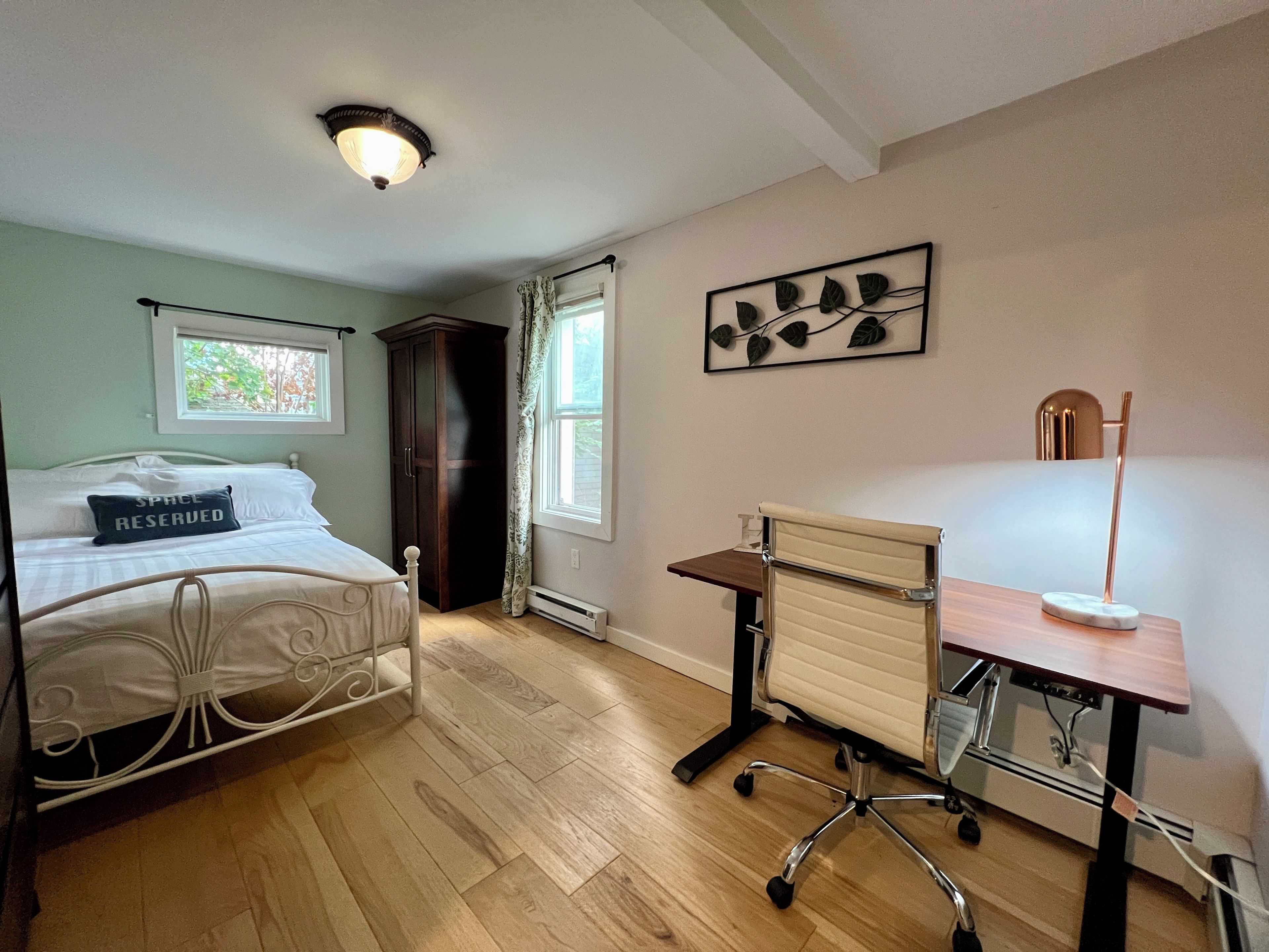 A bedroom with a bed, a desk, and a radiator.