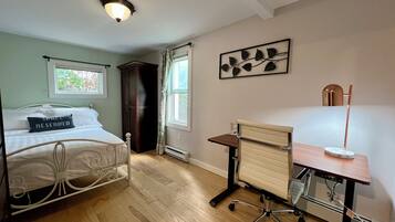 A bedroom with a bed, a desk, and a radiator.