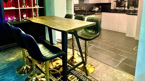 A dining area with a table and chairs, a bar area with shelves, and a kitchen in the background. - Luxury KIA room B2 Private bathroom (Richmond Hill)