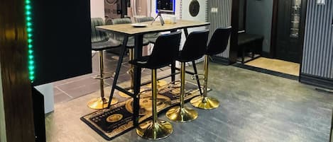 Une cuisine moderne avec un coin repas, comprenant une table ronde et des chaises, un four encastré et un éclairage suspendu.