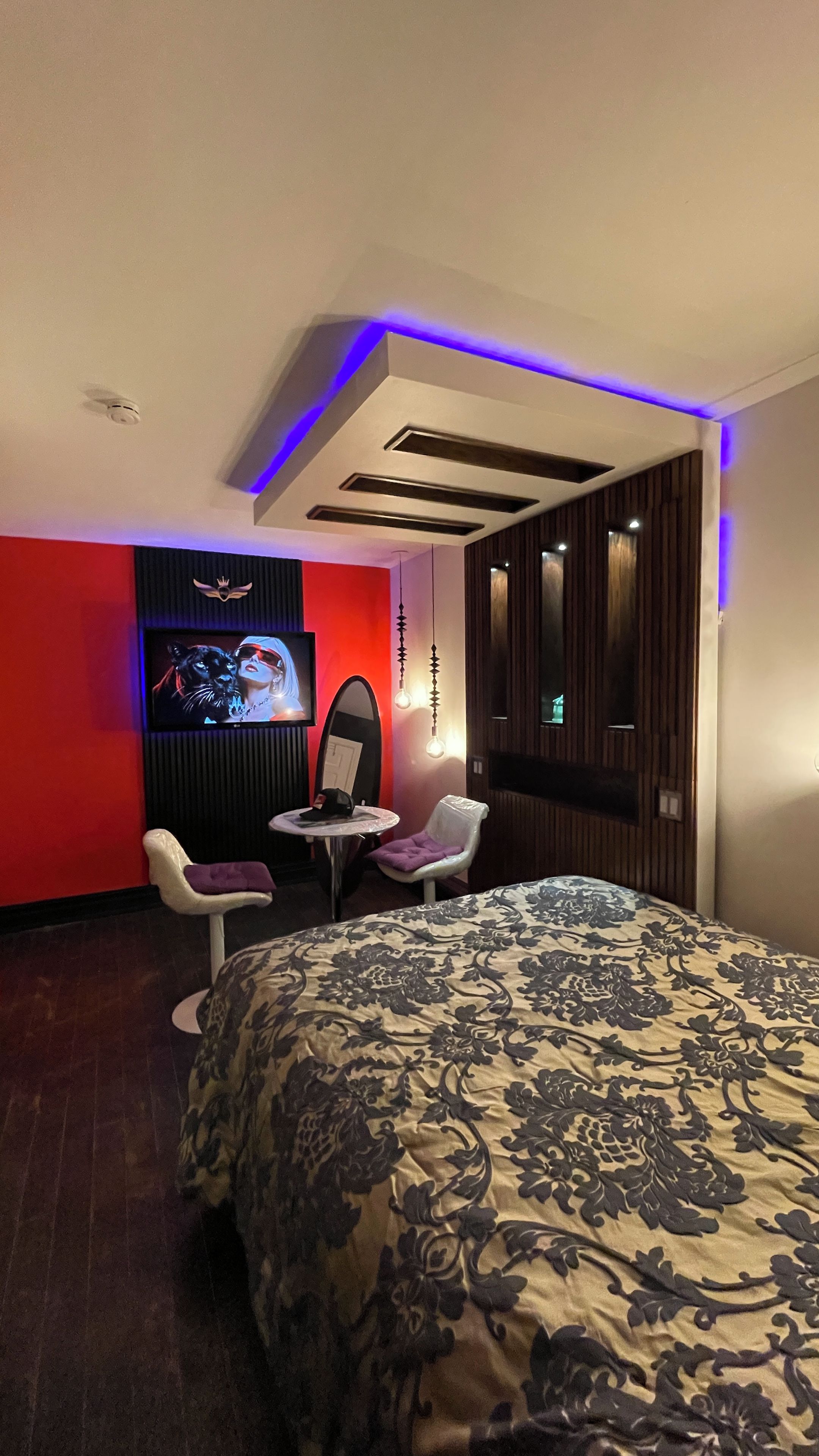 A hotel room with a bed, a TV, a chair, and a small table.