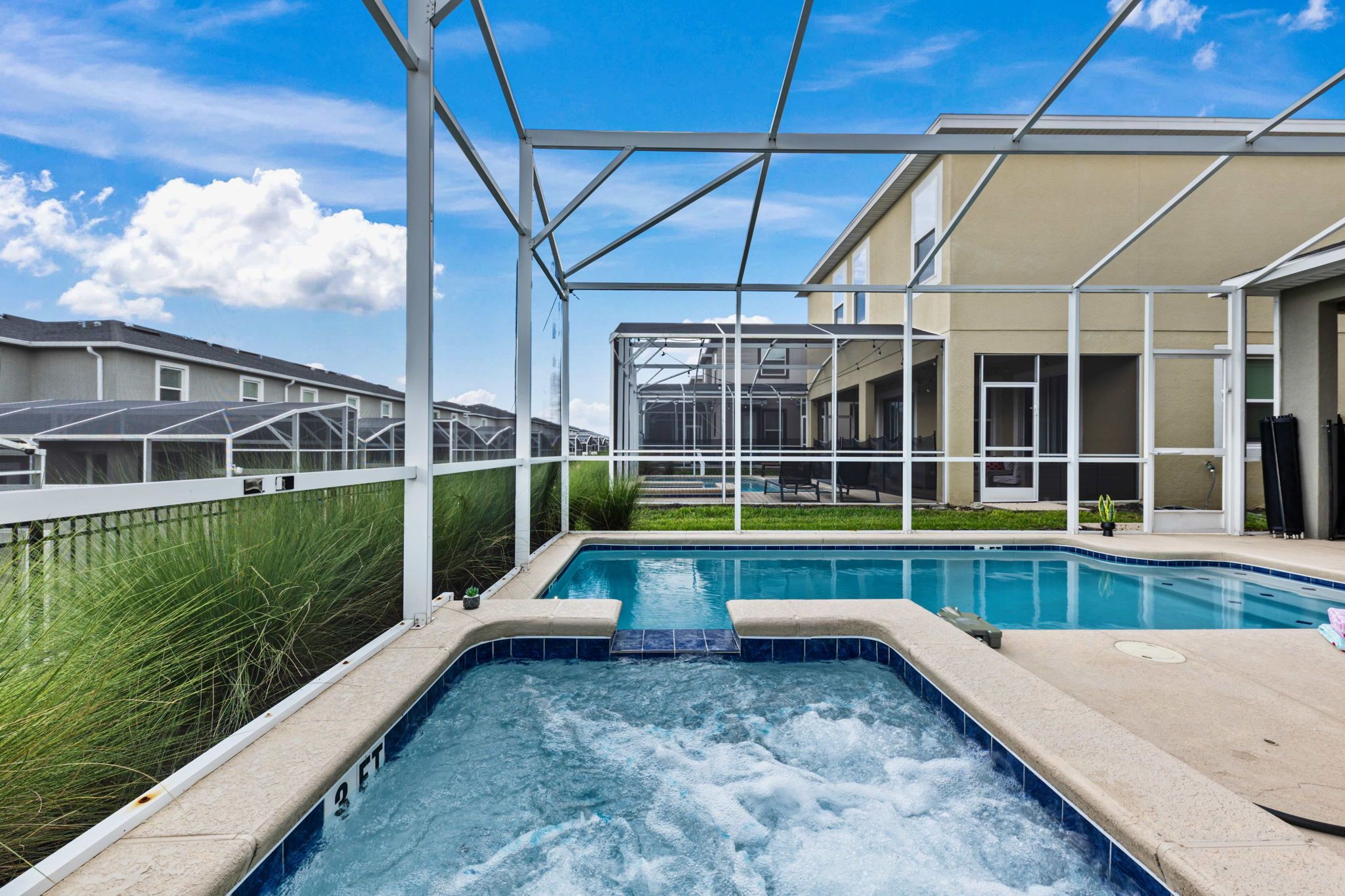 Een zwembad met een jacuzzi, omringd door een overdekt terras met uitzicht op woongebouwen.