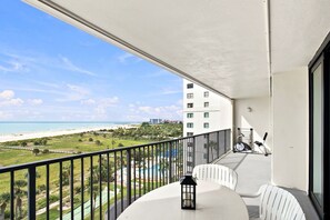 A balcony with a view of a beach and a pool. - Beachfront Condo 2BR Gulf Views Monthly Stays Heated Pool (Clearwater)