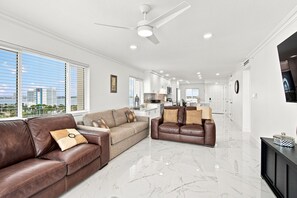A spacious living area with a brown leather sofa, a beige sofa, and a brown leather armchair. - Beachfront Condo 2BR Gulf Views Monthly Stays Heated Pool (Clearwater)